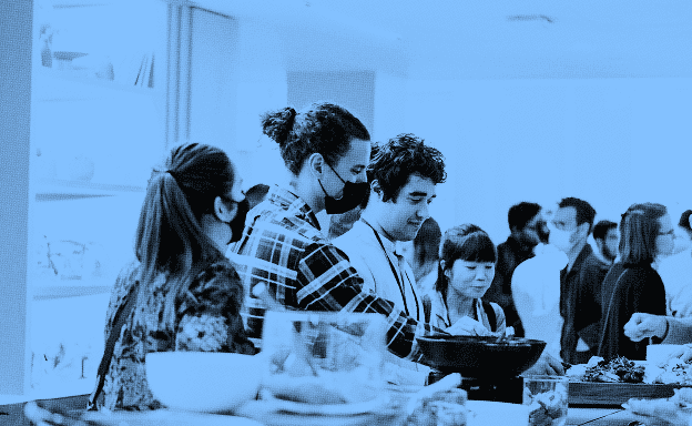 Several people getting food at a conference buffet line