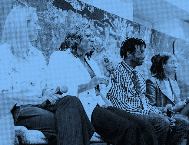 Four people sitting in line with the second one talking to a microphone